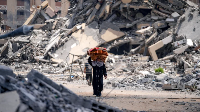 A woman moves with her belongings in a bombed out area of Gaza. - AP